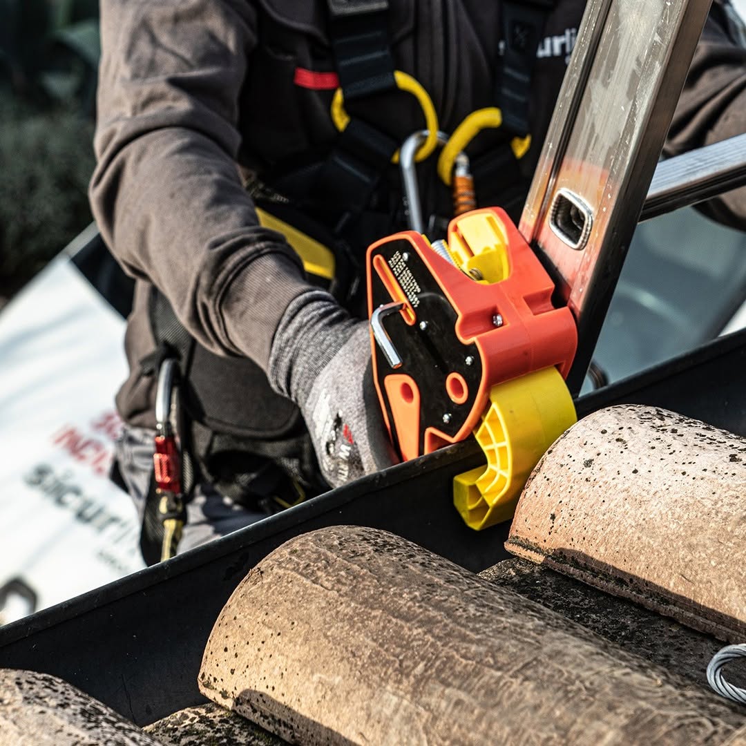 A hand holds a Lock Jaw Ladder Grip attached to a ladder.