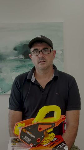 A man wearing glasses and a cap holds a Lock Jaw Ladder Grip and its packaging.